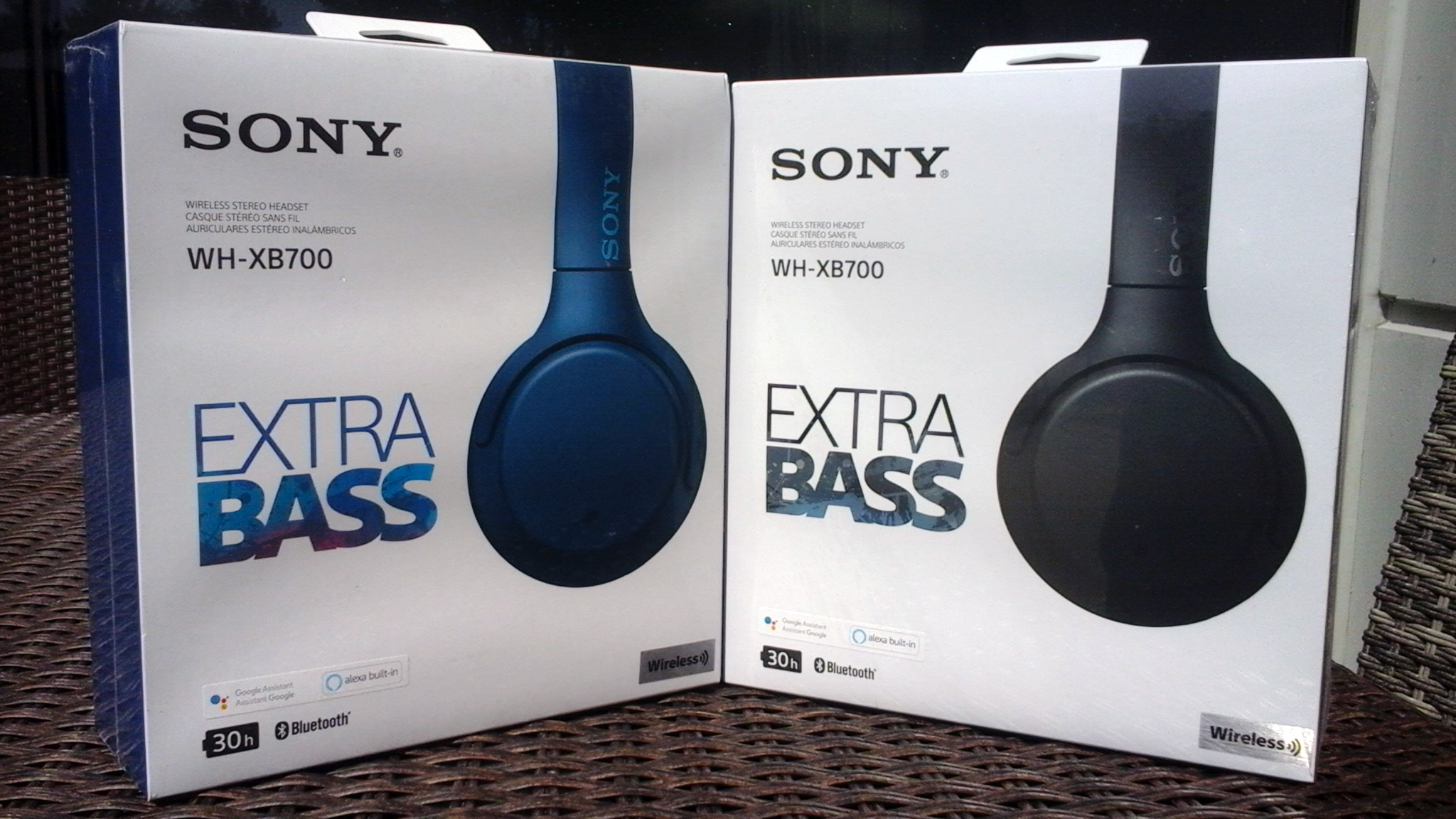 Les deux boîtes blanches contenant les écouteurs WH-XB700 de Sony. Chaque boîte porte le nom « SONY WH-XB700 EXTRA BASS ». Les boîtes sont dehors à la lumière du soleil. La boîte de gauche contient une paire d’écouteurs en bleu, tandis que la boîte de droite contient une paire d’écouteurs en noir.
