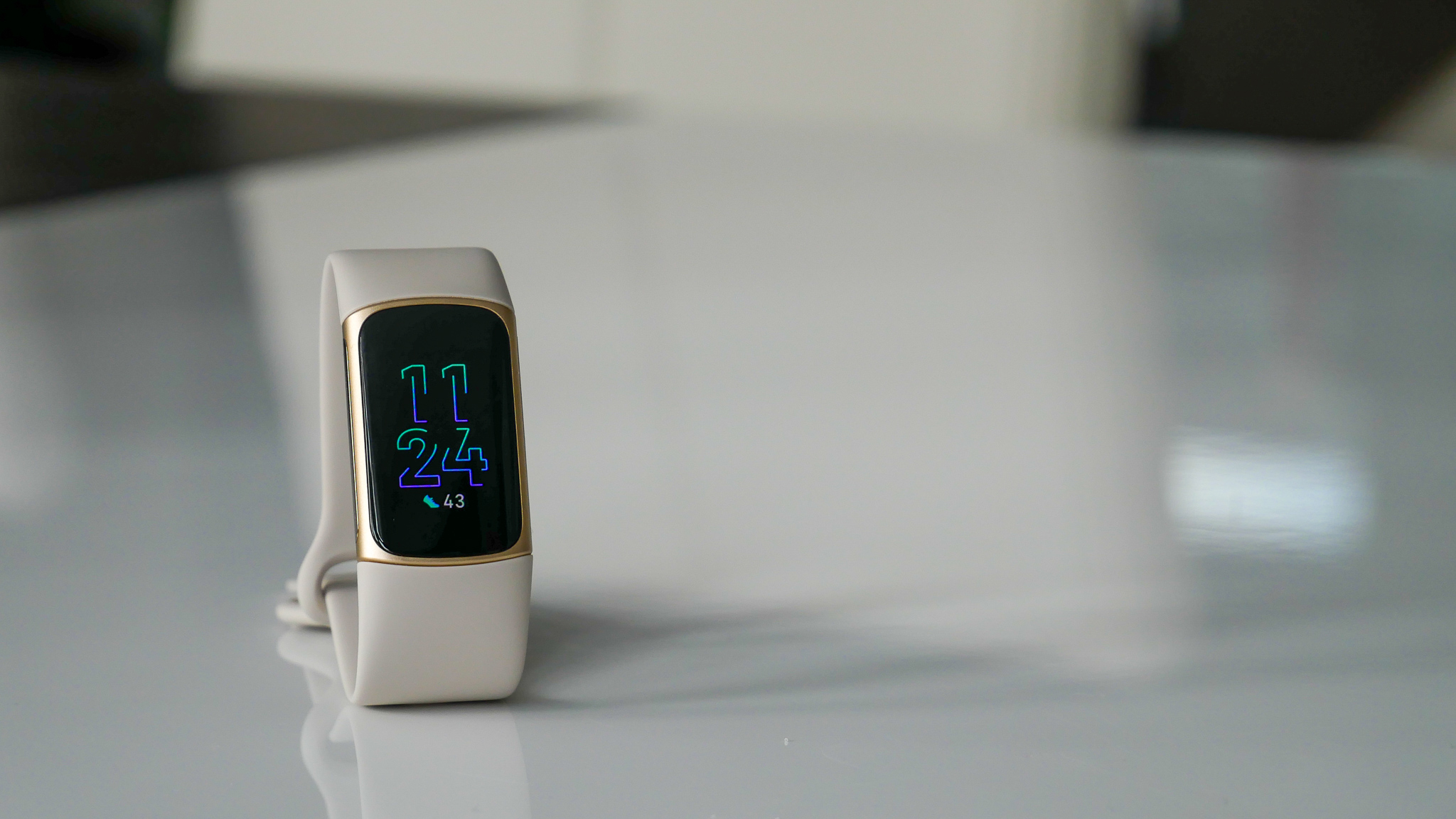 Image of Fitbit Charger 5 on table with clock