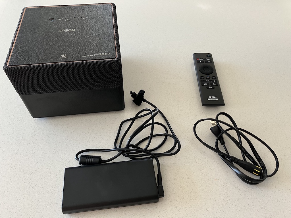 Le projecteur est livré avec une télécommande et un bloc d'alimentation (montré ici avec son câble séparé en deux).
