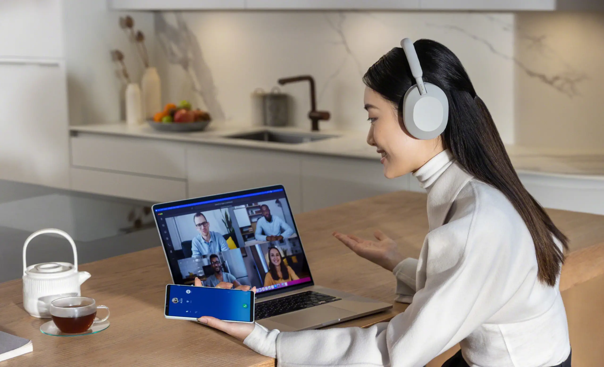 image of women in kitchen on video call using WH-1000XM5 headphones by Sony