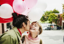 Man Kissing Smiling Girlfriend On Cheek While Giving Her Balloons During Date on Valentines day