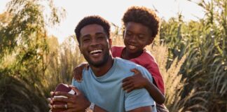 father and son playing baseball in a field. The dad is wearing a Citizen stylish watch.