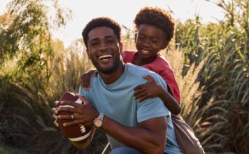 father and son playing baseball in a field. The dad is wearing a Citizen stylish watch.