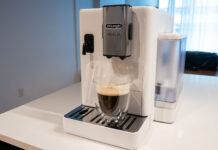 Image de la machine à espresso automatique Rivelia de De'Longhi sur un comptoir de cuisine avec une tasse à café