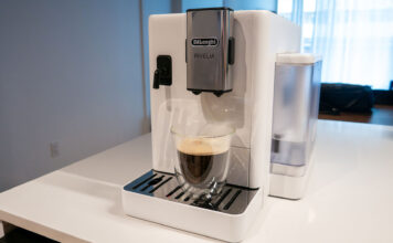 Image de la machine à espresso automatique Rivelia de De'Longhi sur un comptoir de cuisine avec une tasse à café