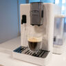 Image de la machine à espresso automatique Rivelia de De'Longhi sur un comptoir de cuisine avec une tasse à café