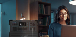 A woman working on her laptop at home in the dark with the Pion portable power station.