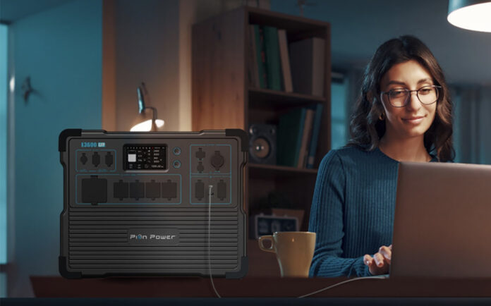 A woman working on her laptop at home in the dark with the Pion portable power station.
