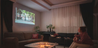 Woman watching home cinema projection - gifts for film lovers - with her dog in the living room at home.