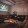 Woman watching home cinema projection - gifts for film lovers - with her dog in the living room at home.