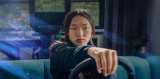 A person playing a game holding a racing sim steering wheel.