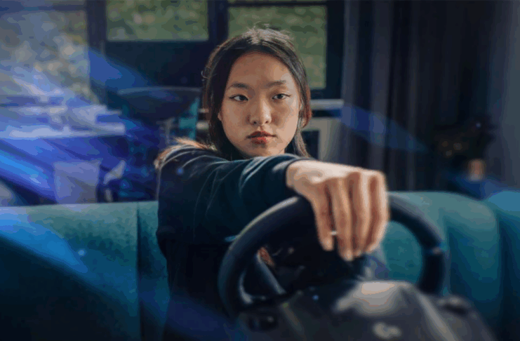 A person playing a game holding a racing sim steering wheel.