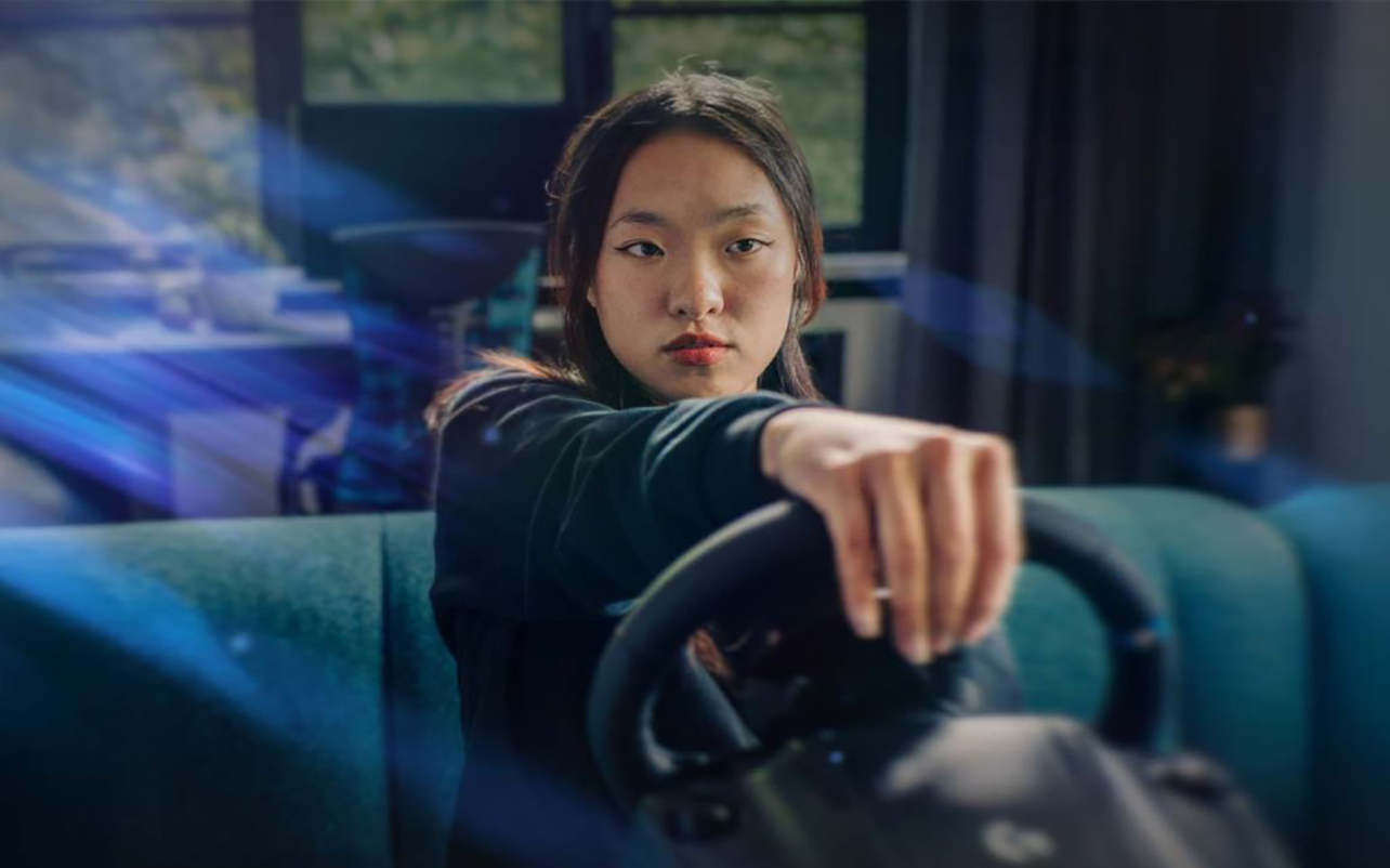 A person playing a game holding a racing sim steering wheel.