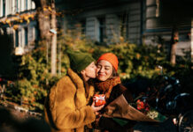 Woman kissing her girlfriend on a cheek on a street